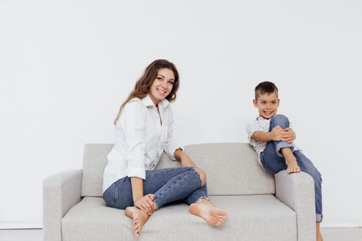 woman sits on the couch next to a cheerful child in a bright room