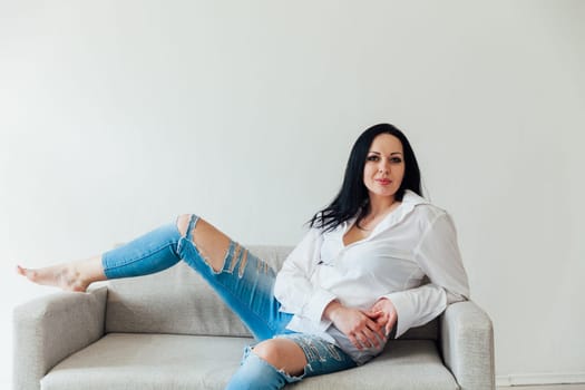 woman in a free style sits in a room on a sofa