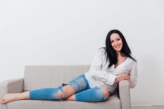 woman in a free style sits in a room on a sofa