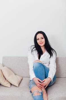 woman in a free style sits in a room on a sofa