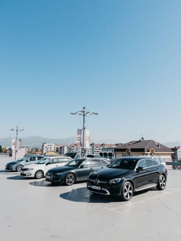 Various cars stand in an open parking lot near the houses. High quality photo