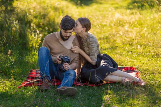 young couple relaxing in nature and looking at photos on a camera