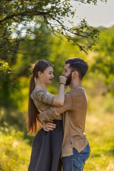 young couple, illuminated by the backlit sun, hugging in nature