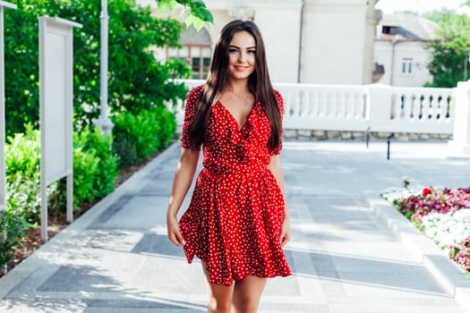 a woman in a red dress walks down the street in the fresh air