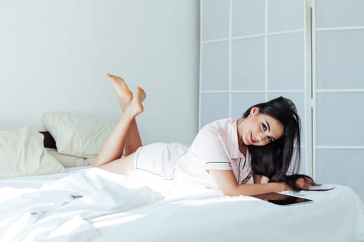 a woman lying on the bed in the morning communication via video link in the tablet