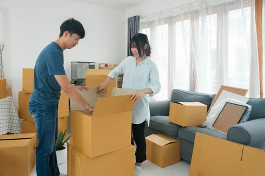 Young married couple moving into new home. They're unpacking or packing card boxes with their accessories. Moving to new house , new house owner concept.