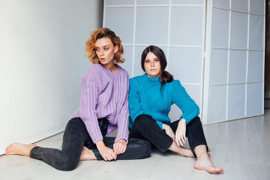friends two women sit on floor and pose in a bright room