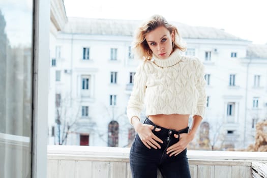 a beautiful blonde woman standing in an apartment on the balcony