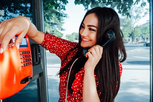 woman in red talking on the phone in a phone booth