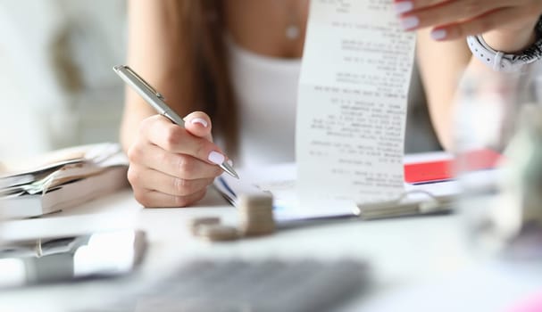 Woman hold silver pen and check in hand. Home budget concept. Wife checks a notes and brings balance