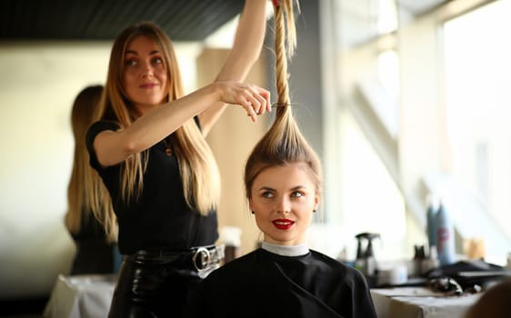 Woman Hairstylist Cutting Female Hair Photography. Hairdresser Using Scissors for Haircut. Young Girl Client Getting Hairdo in Professional Beauty Salon. New Hairstyle for Blonde