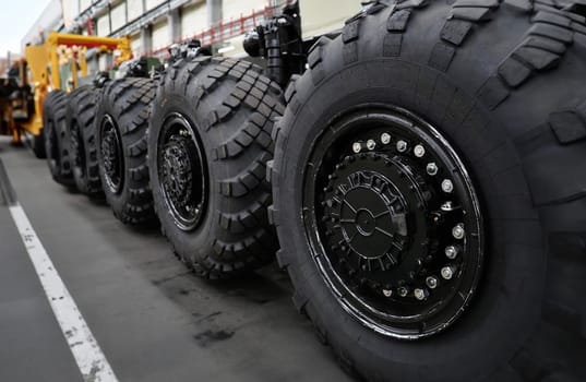 Heavy wheeled tires tractor on assembly line of the plant for transport non-standard cargo unusual background