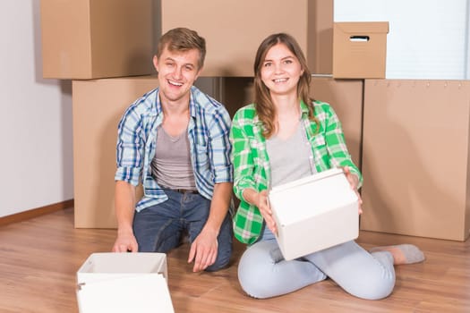 home, people, moving and real estate concept - happy couple with cardboard boxes at new home.