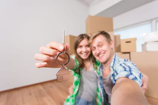 Happy couple showing keys of new home indoor