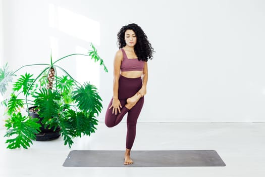 woman does gymnastics for the legs standing on one leg stretching trainer
