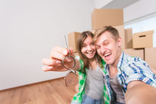 Young married couple with boxes and holding flat keys