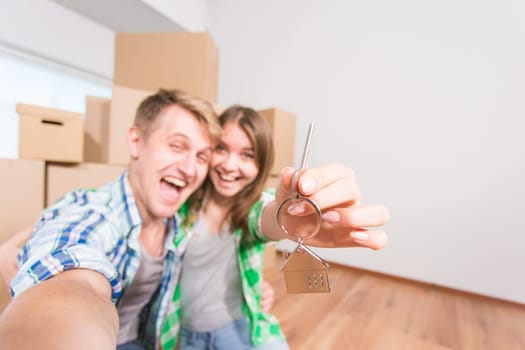 Happy couple embracing and showing house key in their new home