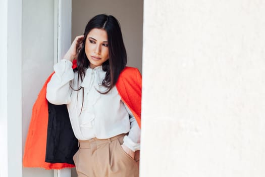 a woman fashionable brunette in a bright jacket business style in the office stands against the wall