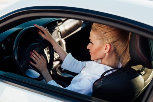 female driver behind the wheel of white car