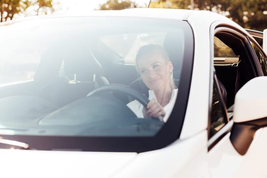 female driver behind the wheel of white car