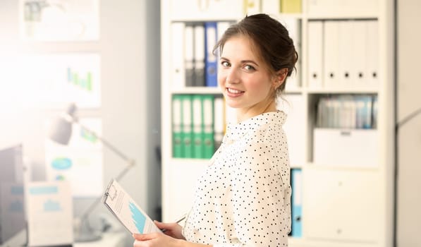 Portrait of manager discussing financial statement. Businesswoman posing in office and looking at camera with gladness. Business meeting concept. Blurred background