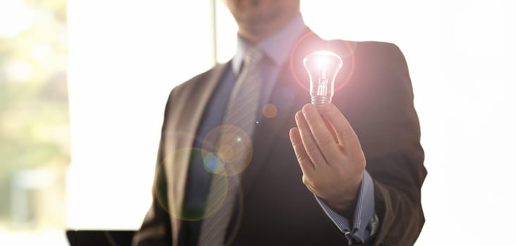 Saving Energy New Solution Innovation Technology. Businessman in Suit Hold Traditional Light Bulb. Male HR Executive Manager with Lamp in Hand. Creative Business Idea. Accounting Finance Concept