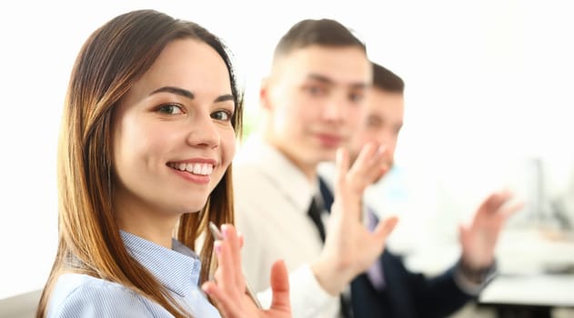 Portrait of gorgeous lady sitting in big modern building and looking at camera with joy. Friendly colleagues discussing important business agreement. Company meeting concept