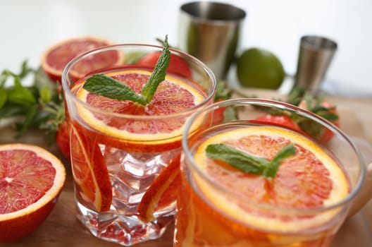 Red orange punch with green mint home made cocktail closeup on wood background