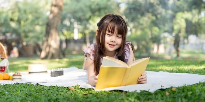 Cute little girl asian read book in park.