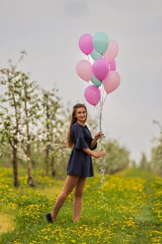 girl with balloons in a young blooming garden