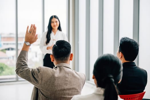 In a seminar classroom, a large group actively participates in the discussion by raising their hands. This dynamic conference audience is brimming with answers.