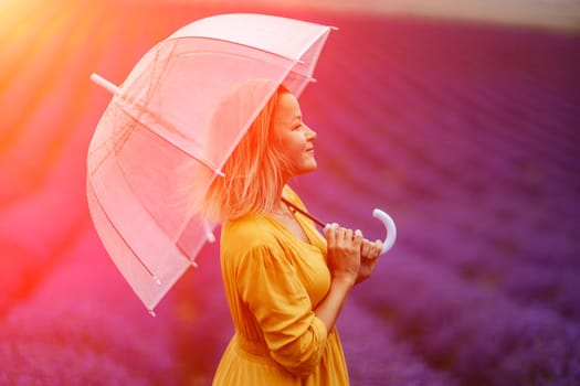 Woman lavender field. A middle-aged woman in a lavender field walks under an umbrella on a rainy day and enjoys aromatherapy. Aromatherapy concept, lavender oil, photo session in lavender.