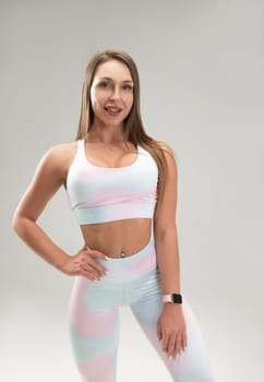 sexy athletic girl in a tight fitness tracksuit on a light background copy paste in studio