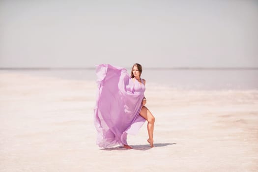 Woman pink salt lake. Against the backdrop of a pink salt lake, a woman in a long pink dress takes a leisurely stroll along the white, salty shore, capturing a wanderlust moment