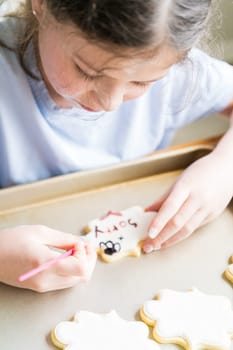 A heartwarming scene of a little girl carefully writing 'Sorry' on sugar cookies with food coloring, the cookies beautifully flooded with white royal icing.