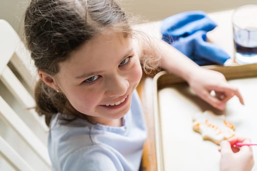 A heartwarming scene of a little girl carefully writing 'Sorry' on sugar cookies with food coloring, the cookies beautifully flooded with white royal icing.