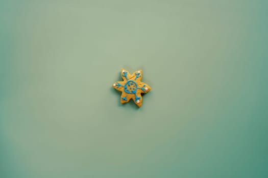 Glazed cookies in the shape of a snowflake lies on a green background. High quality photo