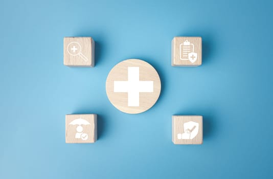 Concept of health insurance and medical. Wooden block with icons about health insurance and access to health care, health care planning on a blue background.