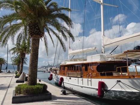 Sailing yacht is moored at the pier with green palm trees. High quality photo