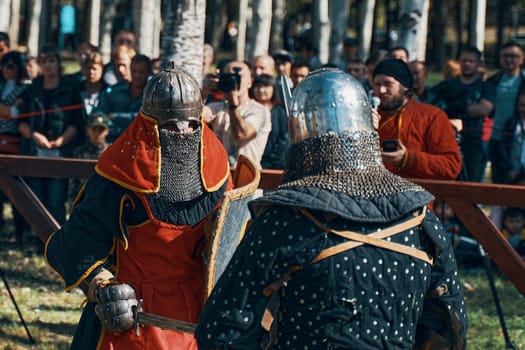 Two knights fight in the arena in front of the audience. Battle in armor with swords. Imitation of medieval jousting tournaments. Bishkek, Kyrgyzstan - October 13, 2019
