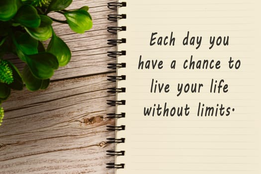 Motivational quote on notepad with potted plant - Each day you have a chance to live your life without limits.