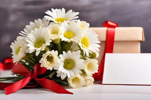 A bouquet of white daisies and a gift box on a table with red satin ribbons, a sheet of notes and red hearts on a light background. Gift for Valentine's Day