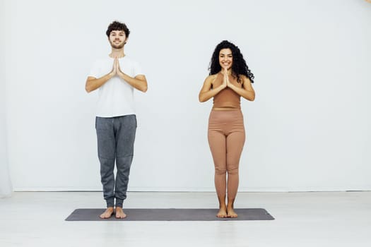 man and woman stand in yoga namaste pose greeting relaxation workout sport