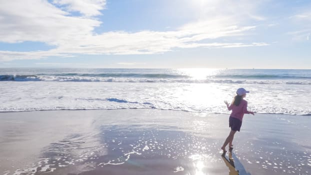 A little girl joyfully plays on the vast, empty sands of El Capitan State Beach in California during winter.