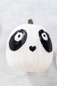 Painting panda face with black acrylic paint to make panda pumpkin for Halloween.