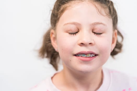 Little girl with rainbow braces smiling at the camera.