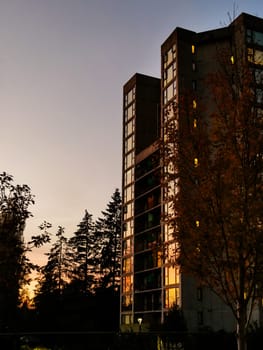 Sunset in a city. High-rise residential building on sunset sky background.