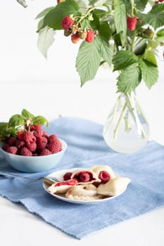 Slavic dish vareniki with fresh raspberries, Still life on a blue background with a bouquet of fresh raspberries on a branch. High quality photo