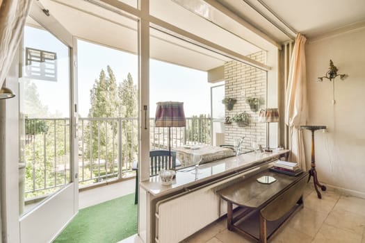 a living room with a desk and chair in front of the window looking out onto the patio area to the trees outside