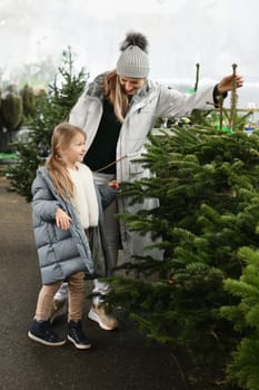 Mother and child buying a Christmas tree in the market.